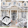 White spider web decor with black spiders, draped across outdoor house facade