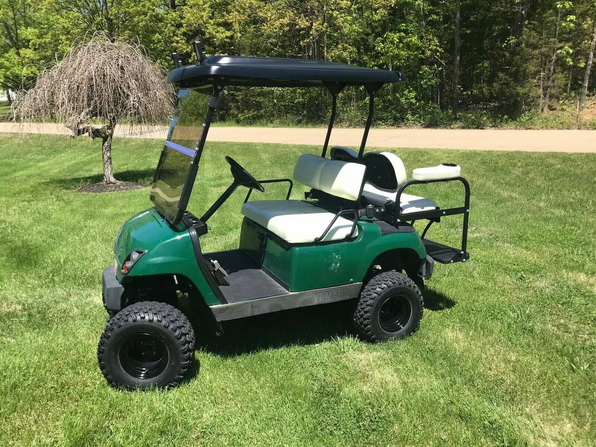 Tinted folding windshield on a green golf cart outdoors
