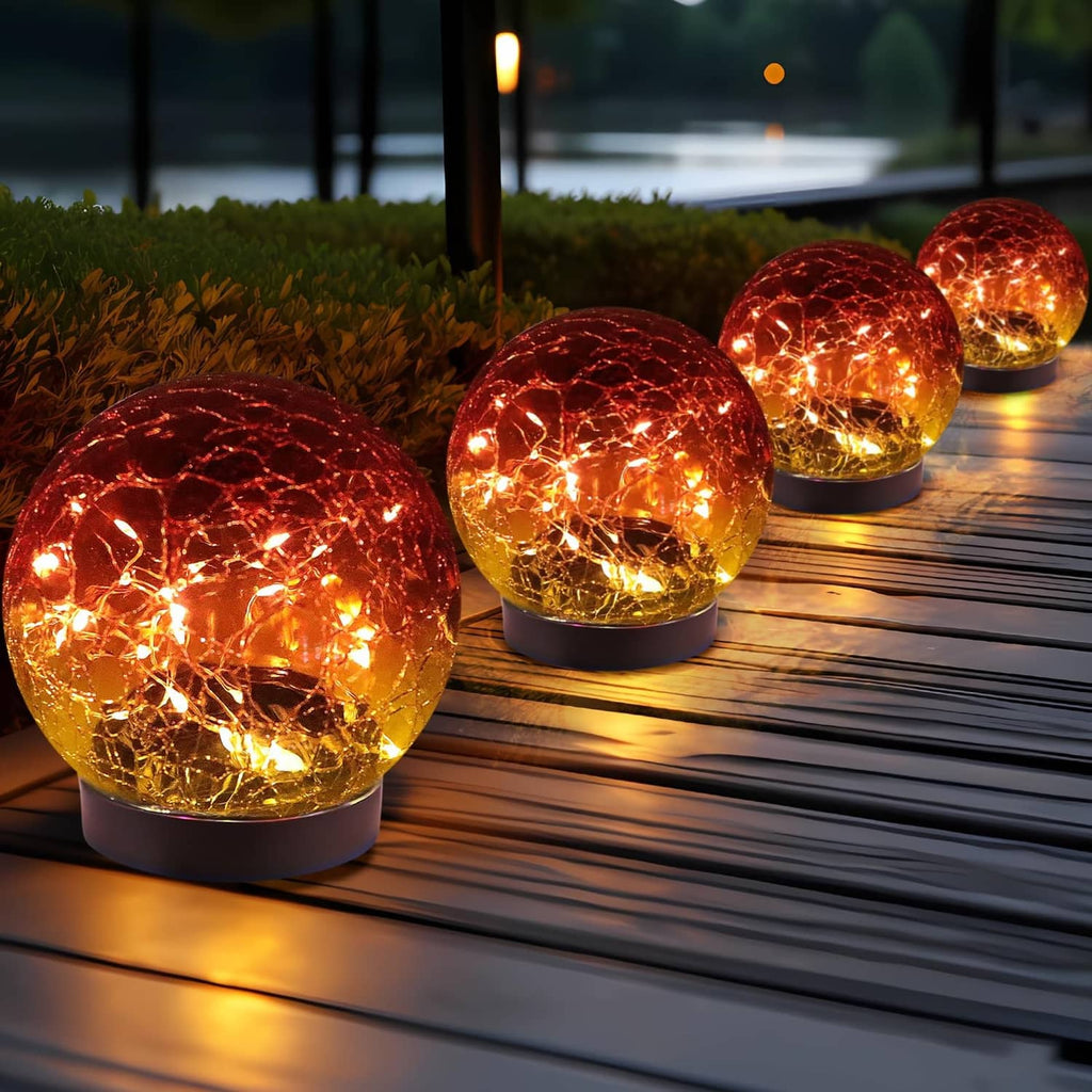 Set of 4 glowing red gradient glass solar globe lights on wooden deck