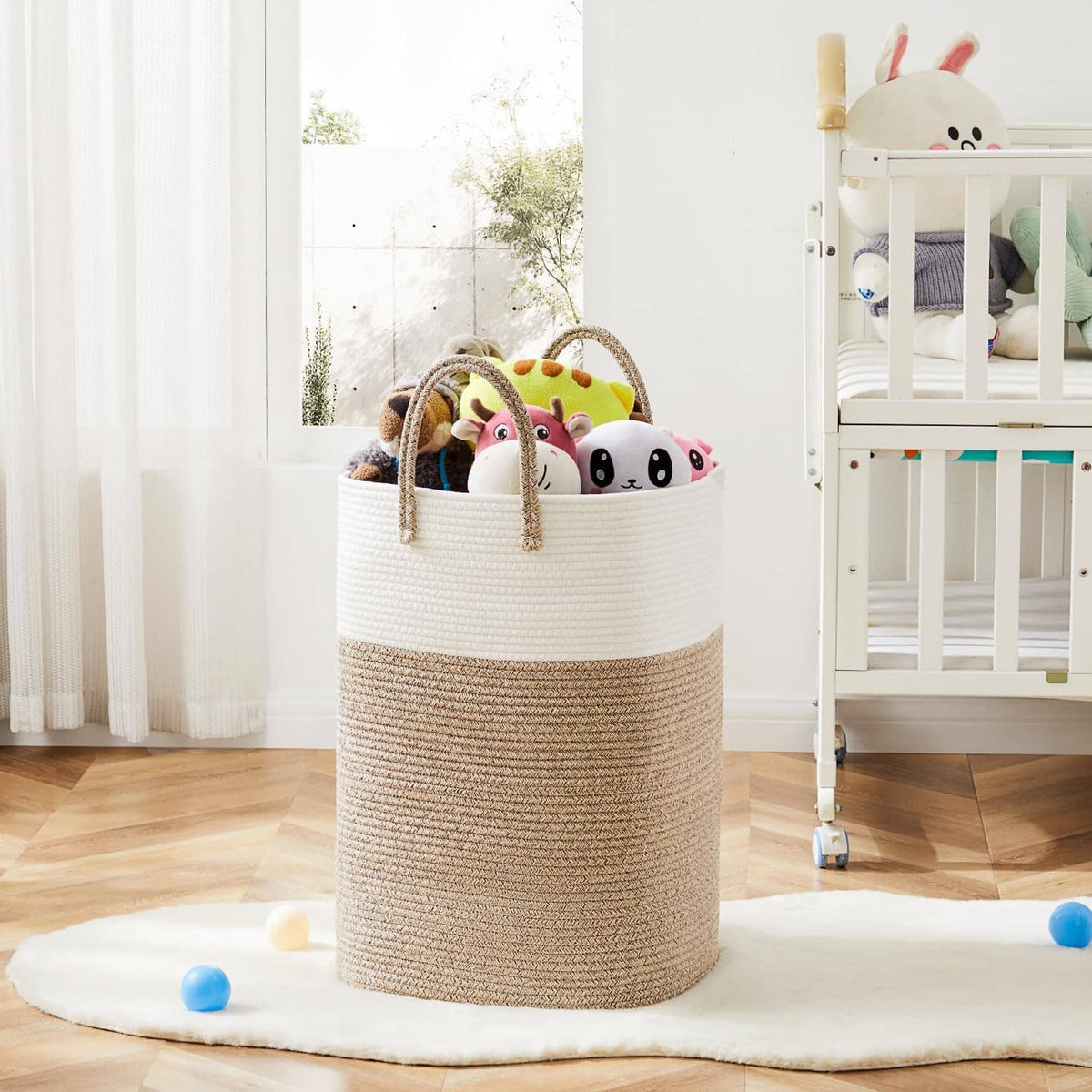 Two-tone woven cotton rope laundry hamper with carry handles, filled with plush toys.