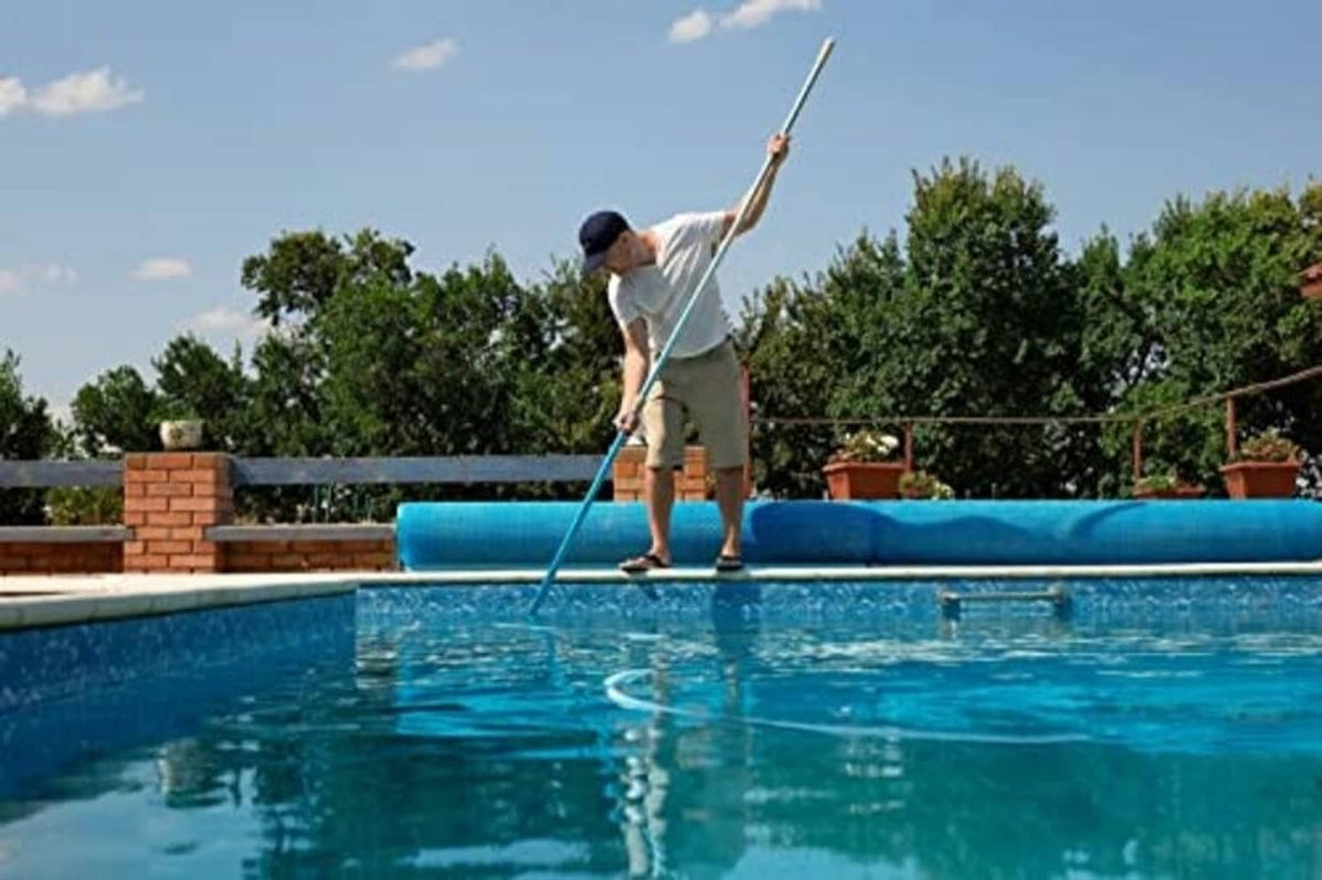 Telescopic swimming pool cleaning pole extended over pool water, blue anodized aluminum