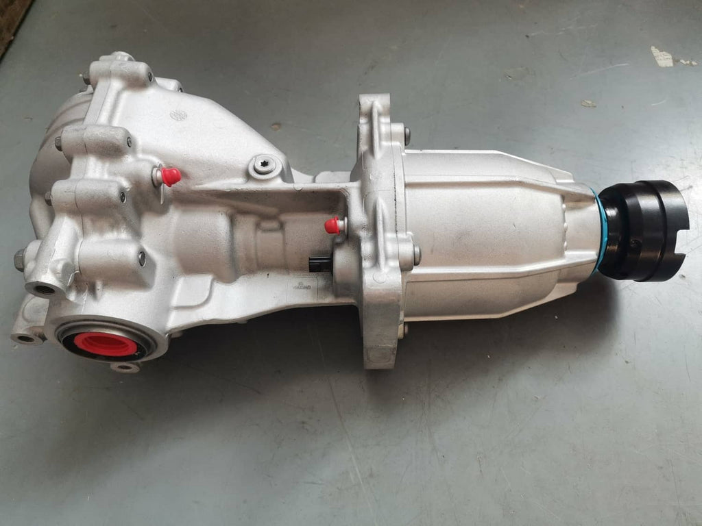 Rear differential assembly with silver housing and axle shaft, side view on a work surface.