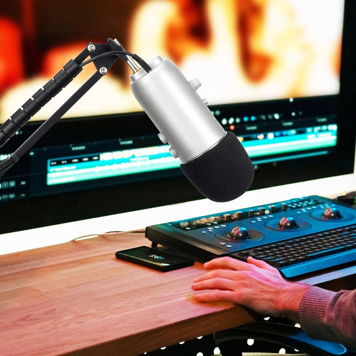 Black foam windscreen on a silver microphone near a computer keyboard