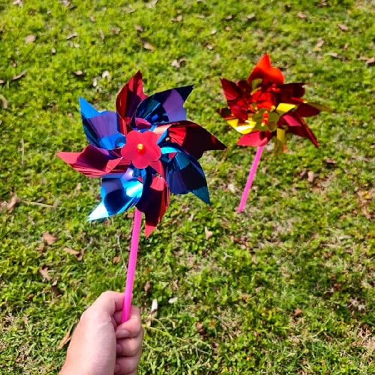 Close-up of multicolor plastic pinwheel with pink handle, held in hand