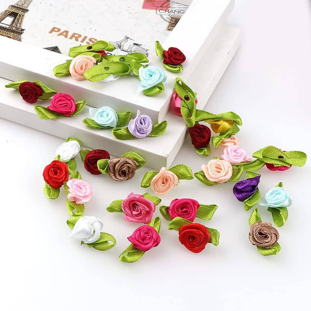 Mini ribbon rose sprigs with green leaves scattered across a gift box