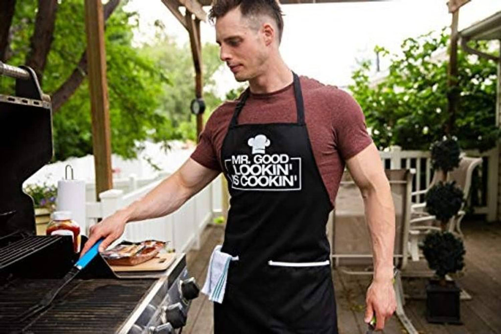 Black cooking apron with chef hat logo graphic, worn over a maroon T-shirt