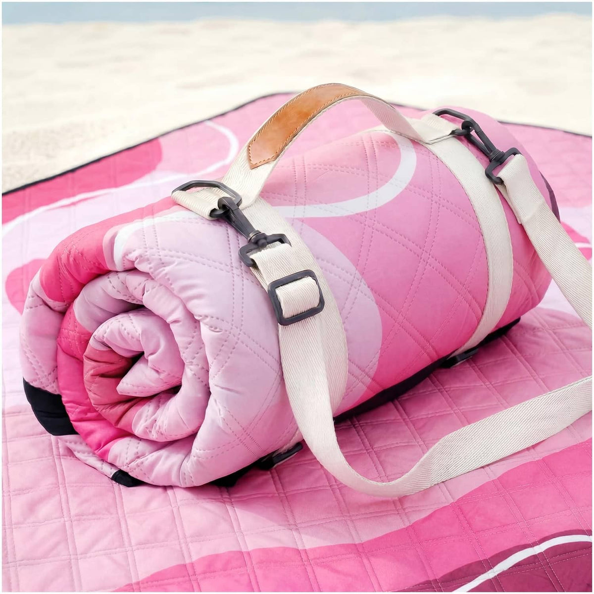 Pink waterproof picnic blanket roll-up with beige straps and black buckles