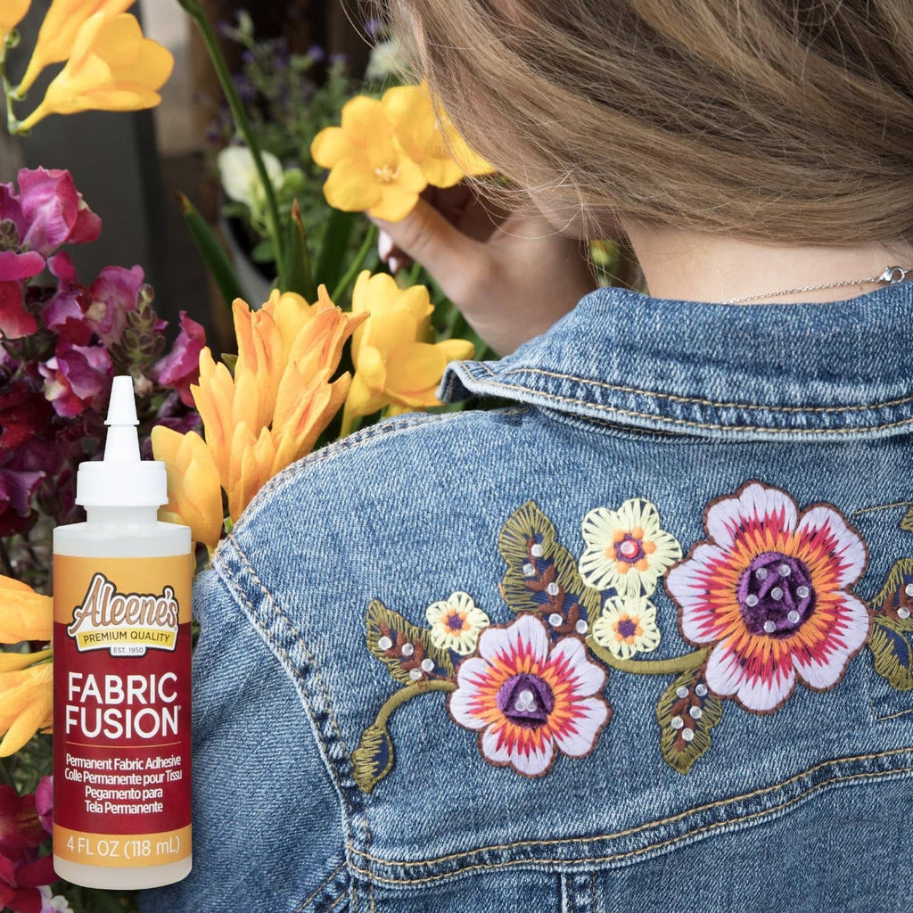Denim jacket with floral applique and Aleene's Fabric Fusion bottle near the sleeve.