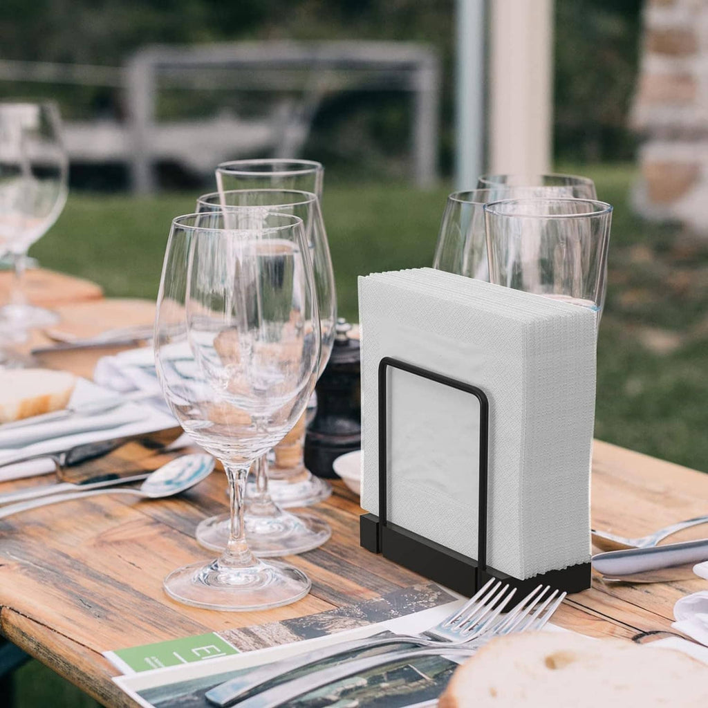 Napkin holder on outdoor dining table with white napkins and black metal frame.