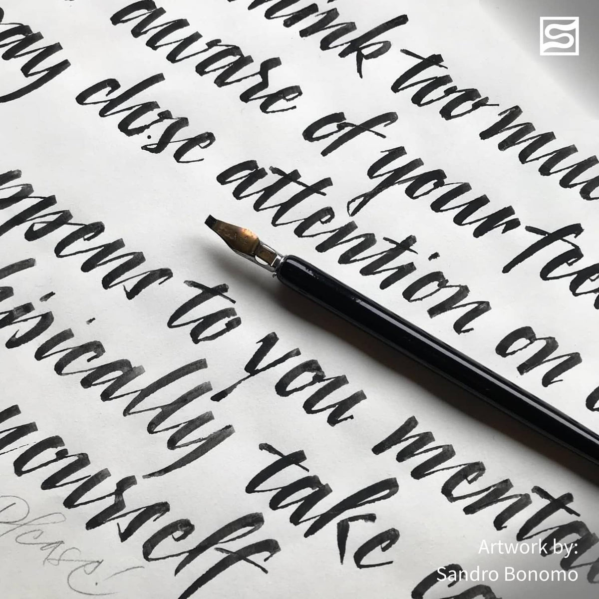 Calligraphy pen applying black ink to paper, close-up of letterforms
