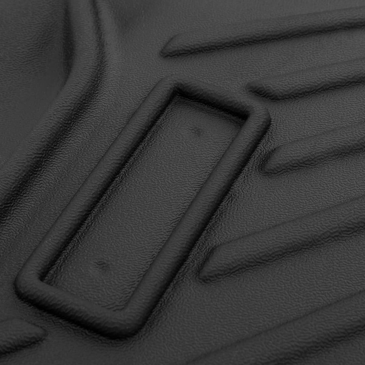 Close-up of black molded floor mat traction grooves with raised border