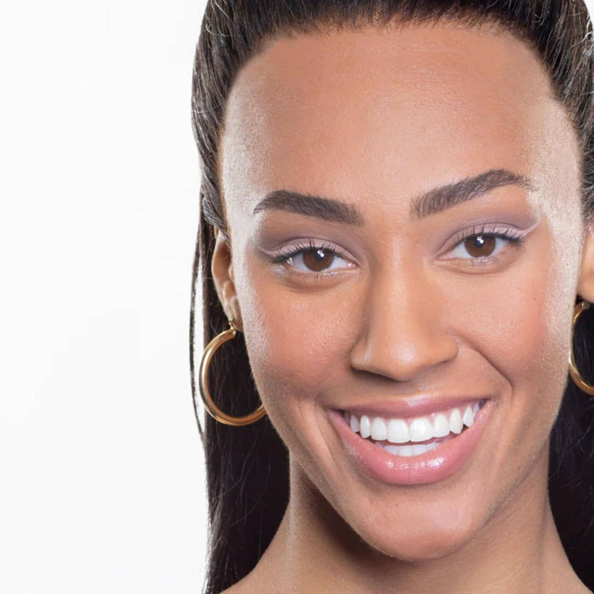 Smiling woman with matte nude eye makeup and glossy lips; close-up portrait