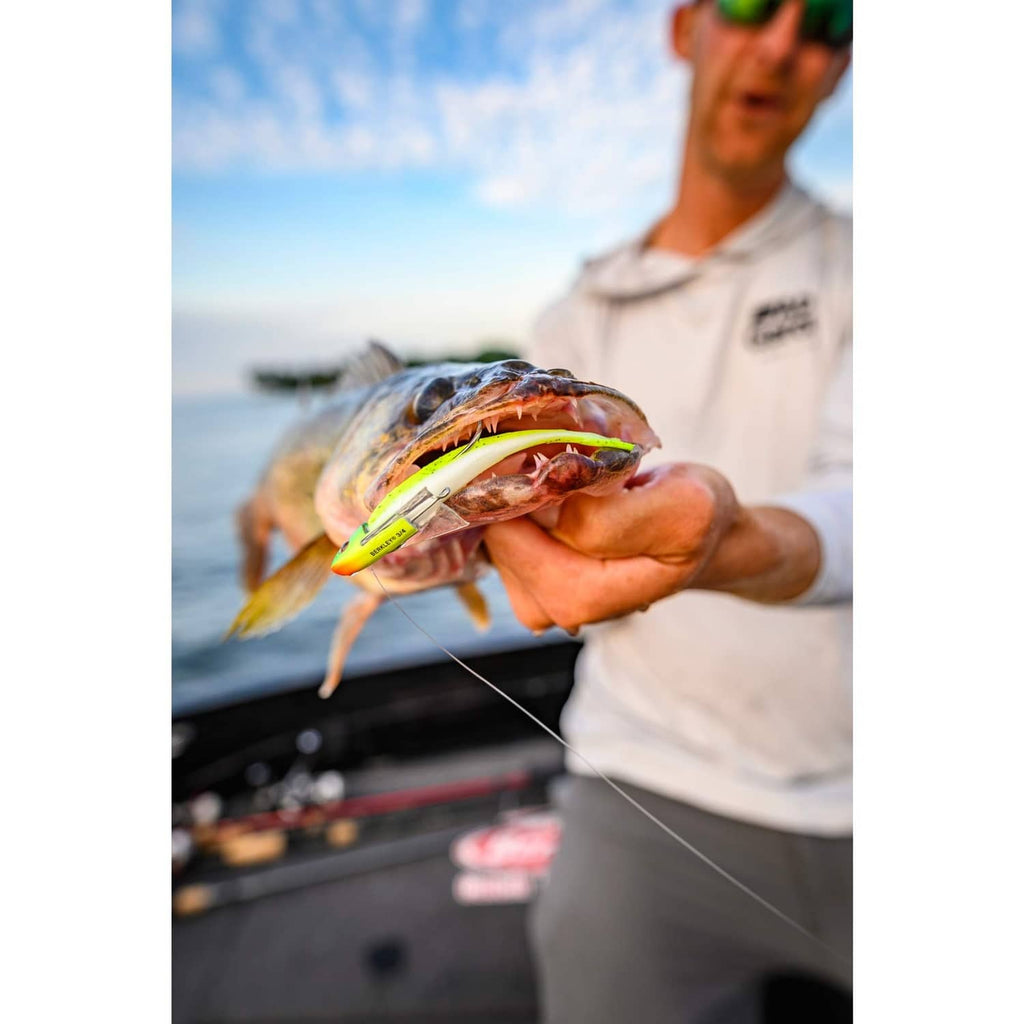Man holding fish with neon green lure and hook attached at mouth