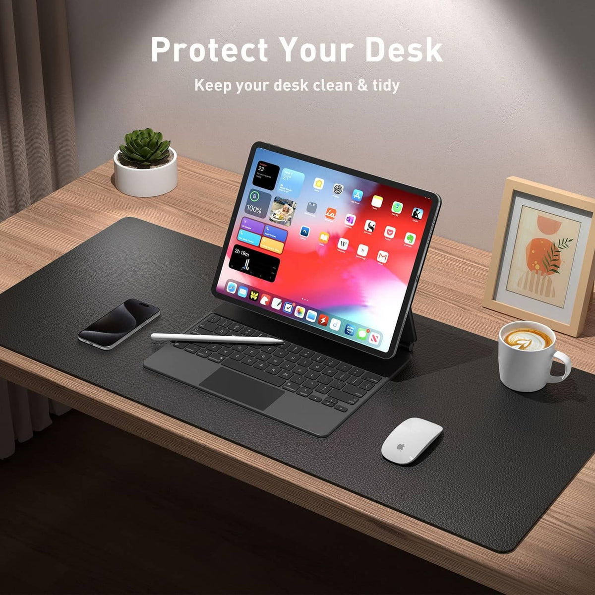 Black PU leather desk pad on wooden desk under a laptop, mouse, and cup