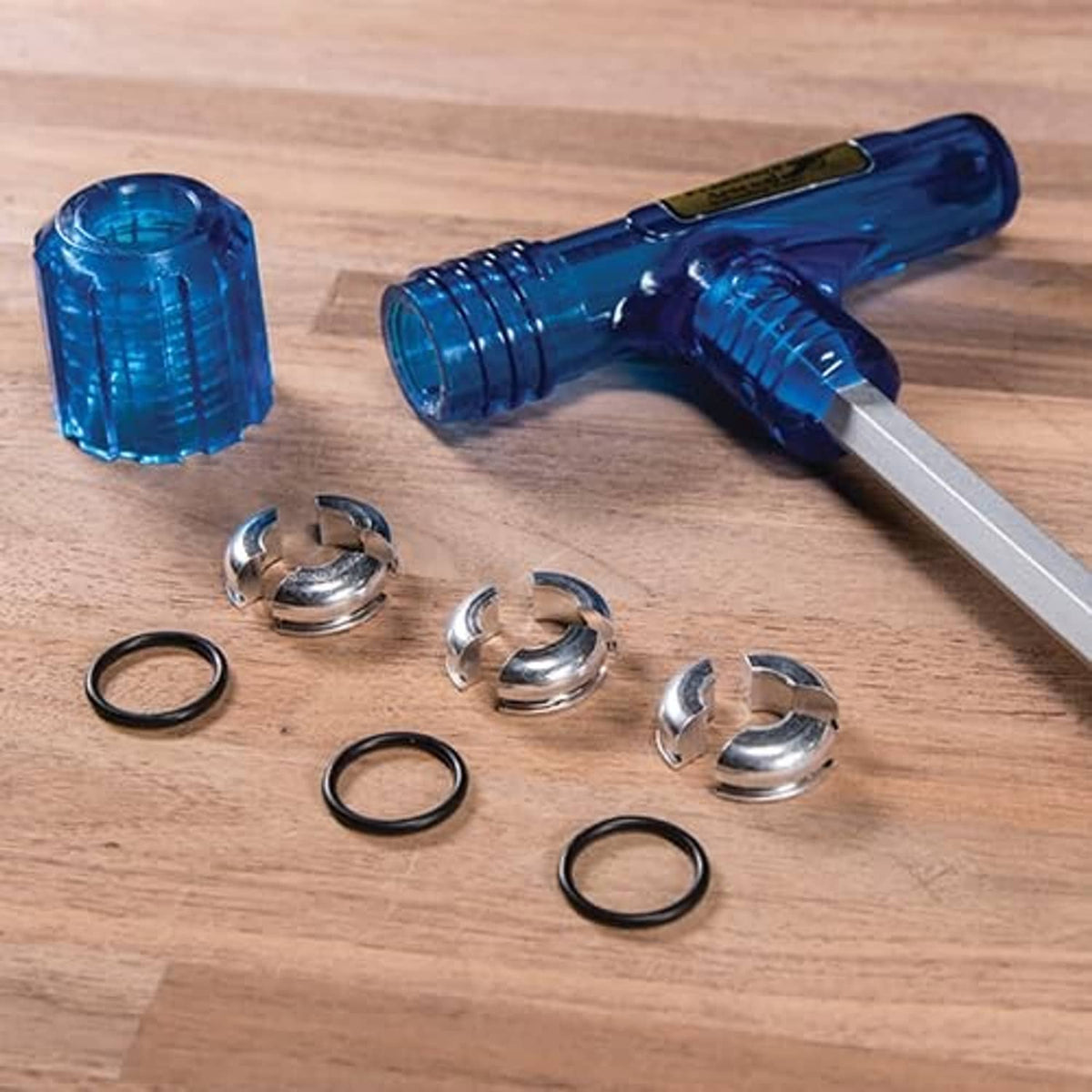 Blue impact bullet puller tool with metal shaft and collet pieces on wood