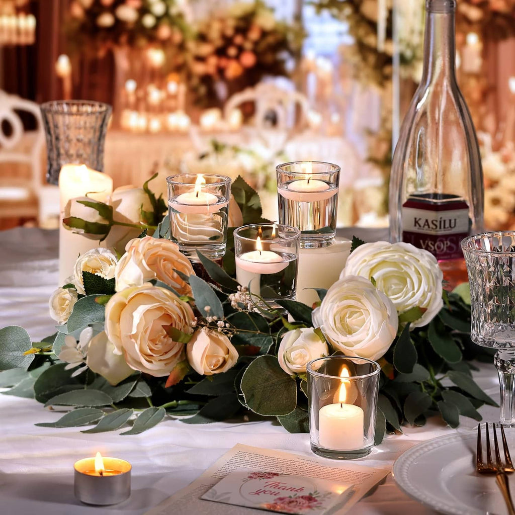 Clear glass votive holders with lit tea lights on a decorated event table