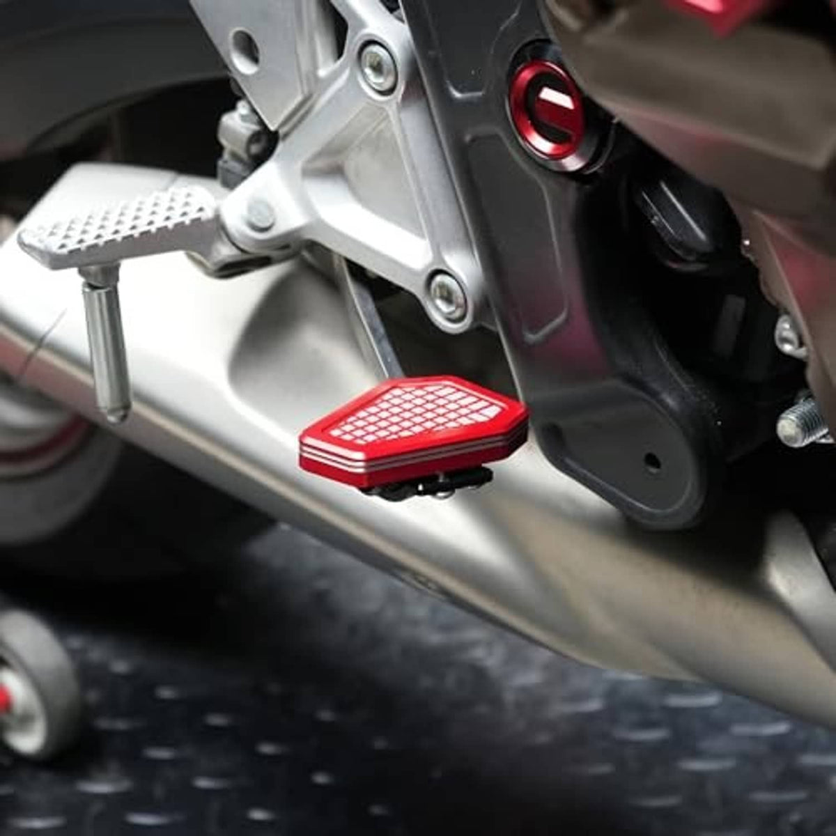 Red anti-slip grid brake lever pedal extender attached to motorcycle frame