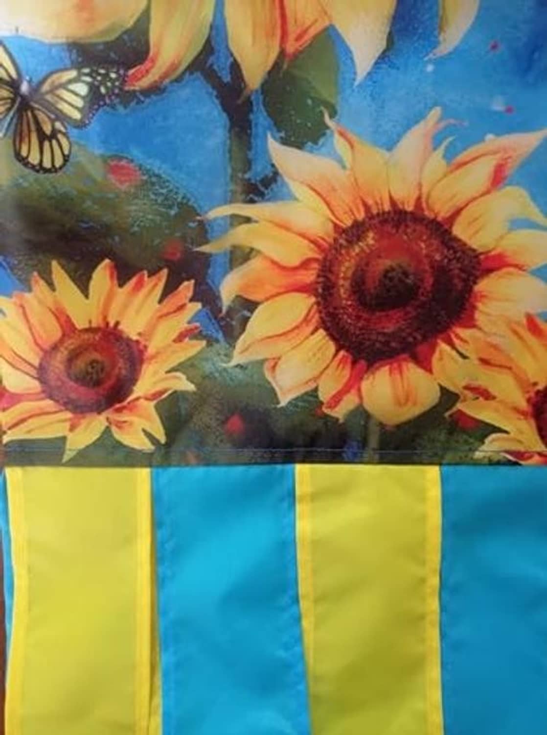 Close-up sunflower and butterfly design on blue windsock fabric with striped bottom