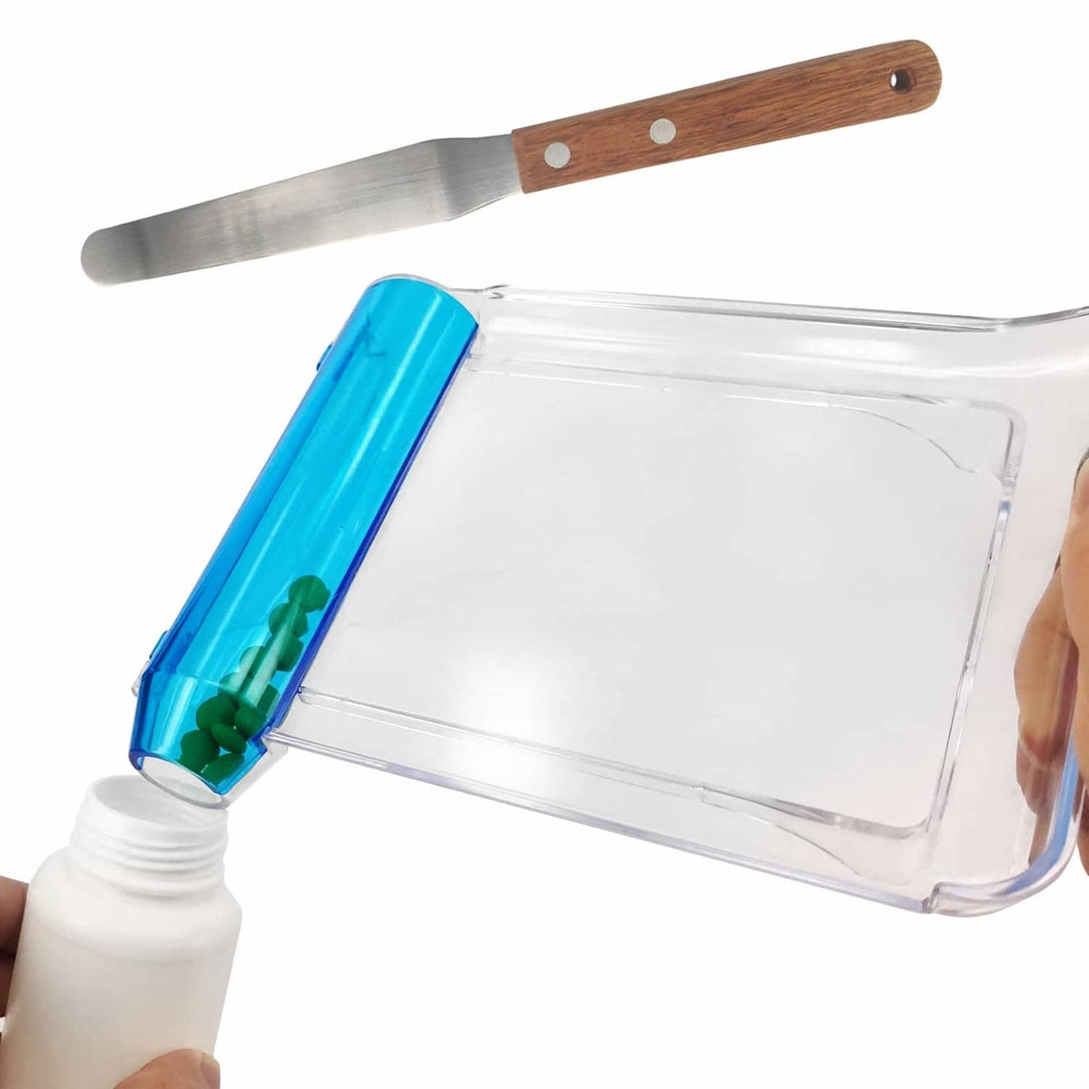 Pill counting tray with blue pusher, clear base, wooden spatula handle, green pills