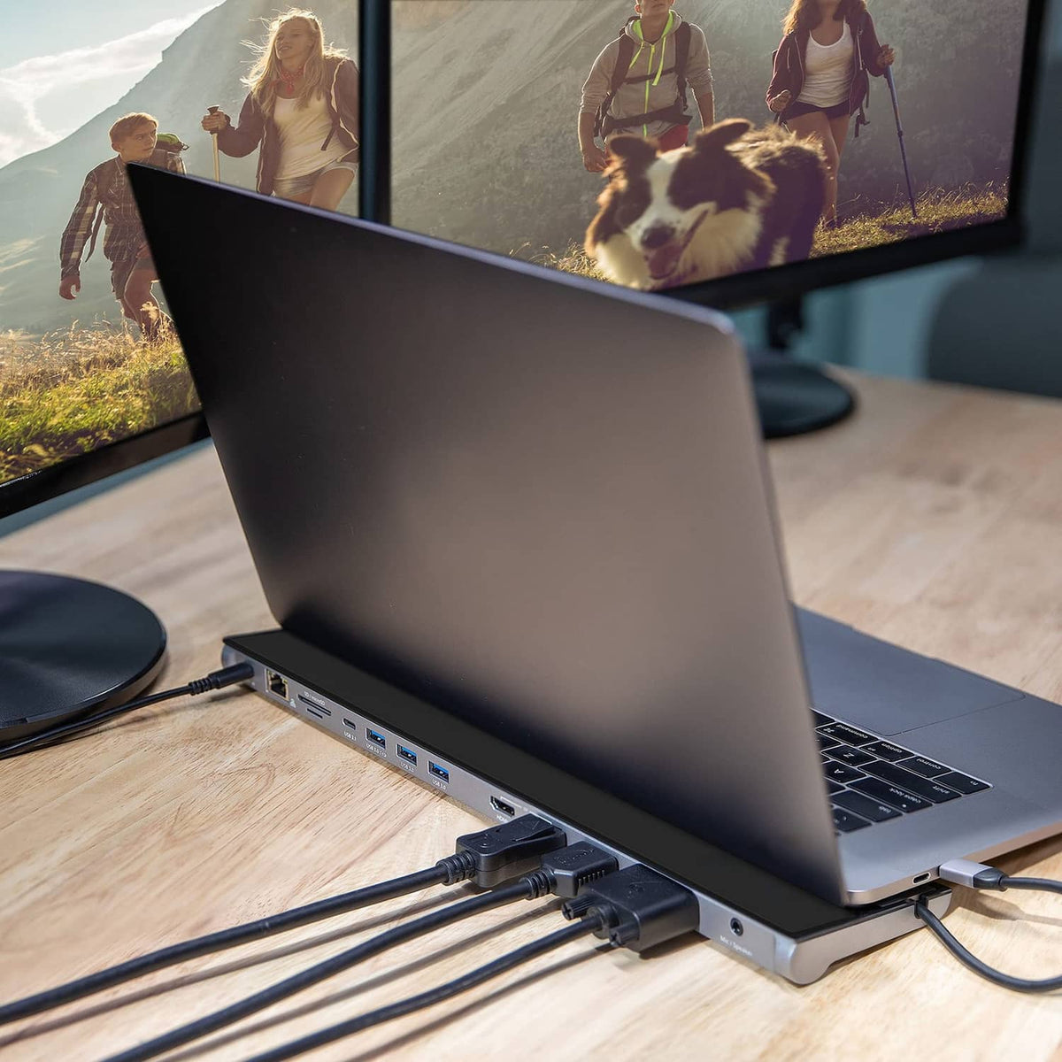 Black USB-C docking station connected to laptop with visible side ports and cables