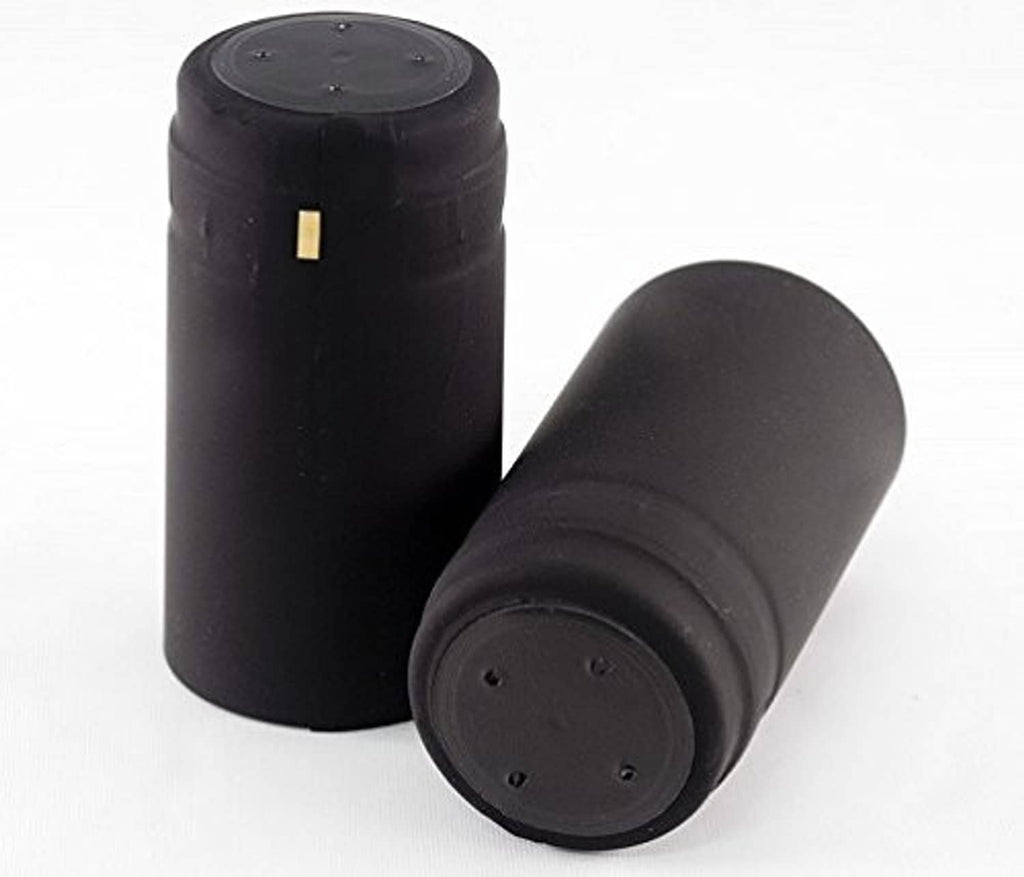 Matte black cylindrical shrink wine caps, one upright and one tilted, with yellow tab