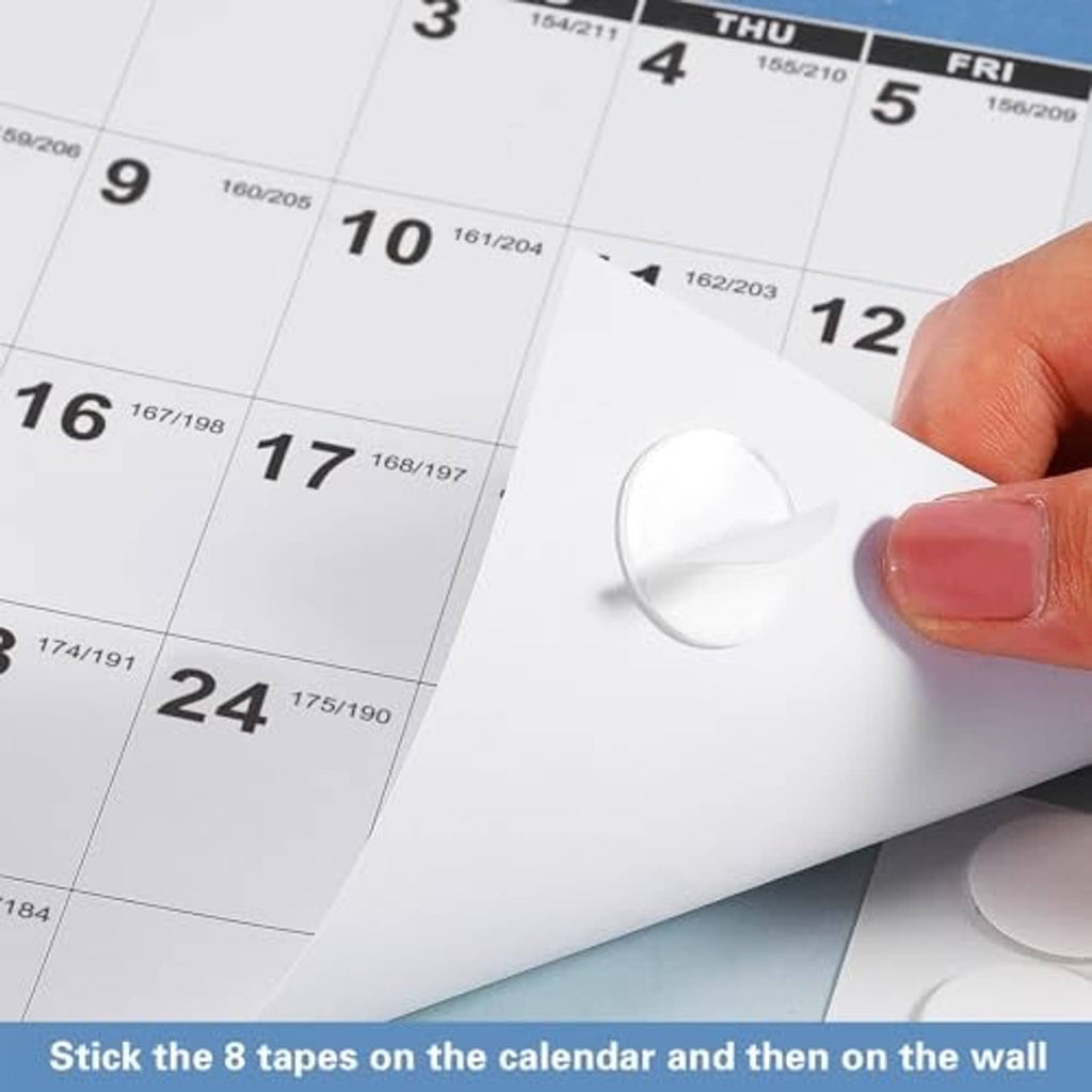 Hand applying a white tape strip to a 2027 calendar sheet for wall mounting.