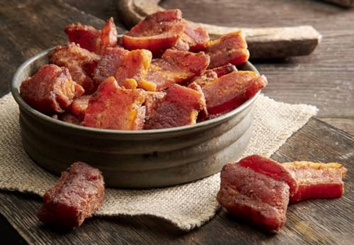 Bowl of smoked pork belly bites with browned cubes on a cloth-lined dish