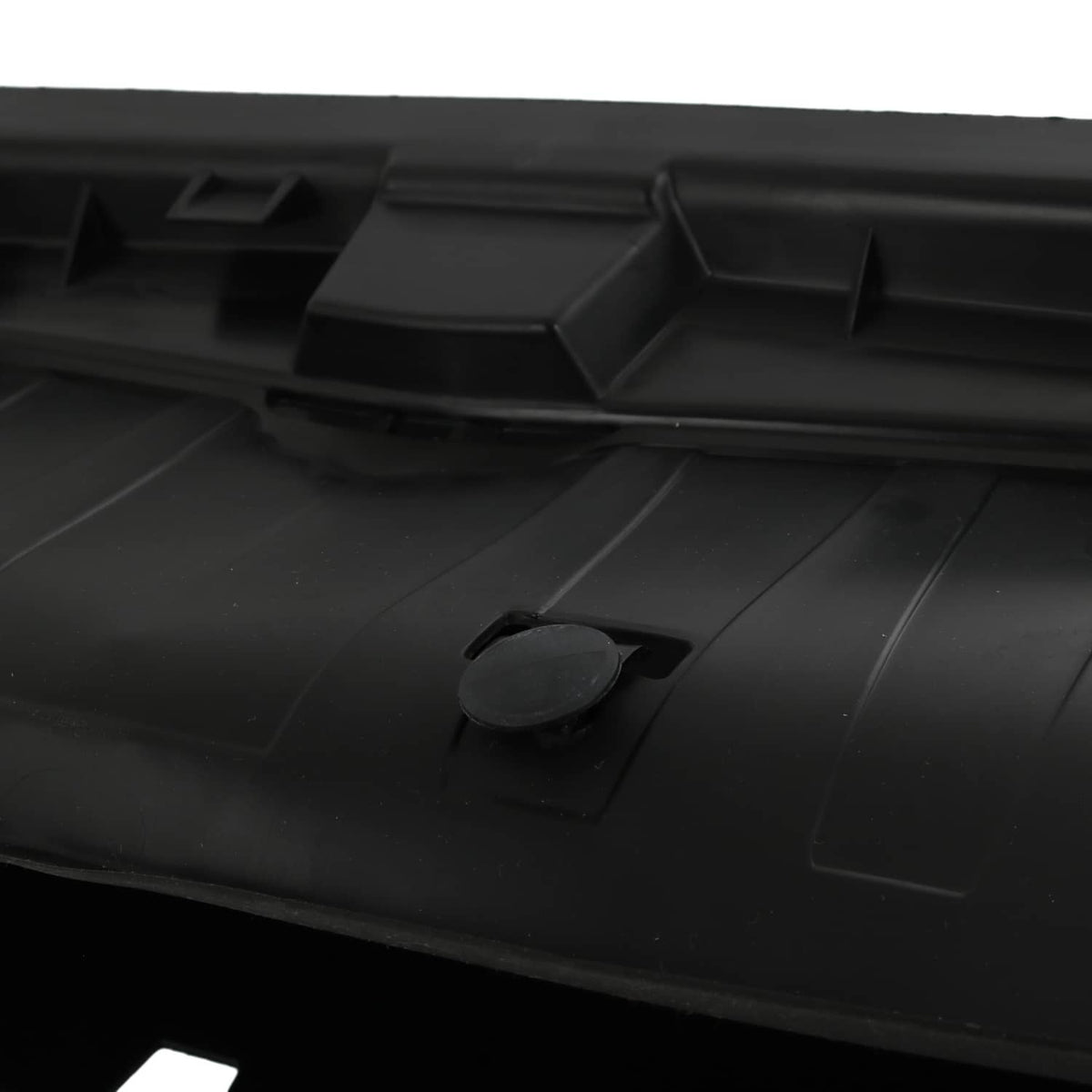 Close-up of black radiator shutter cover panel with small round access plug