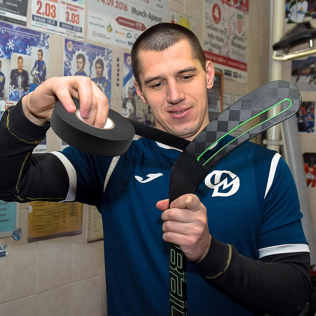 Person applying black hockey tape to a hockey stick handle with strong adhesive