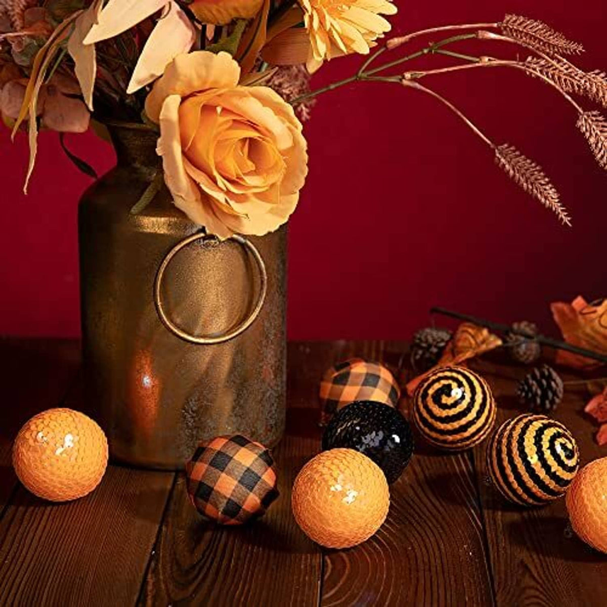 Assorted black and orange sequin ball ornaments with plaid and spiral patterns on a display