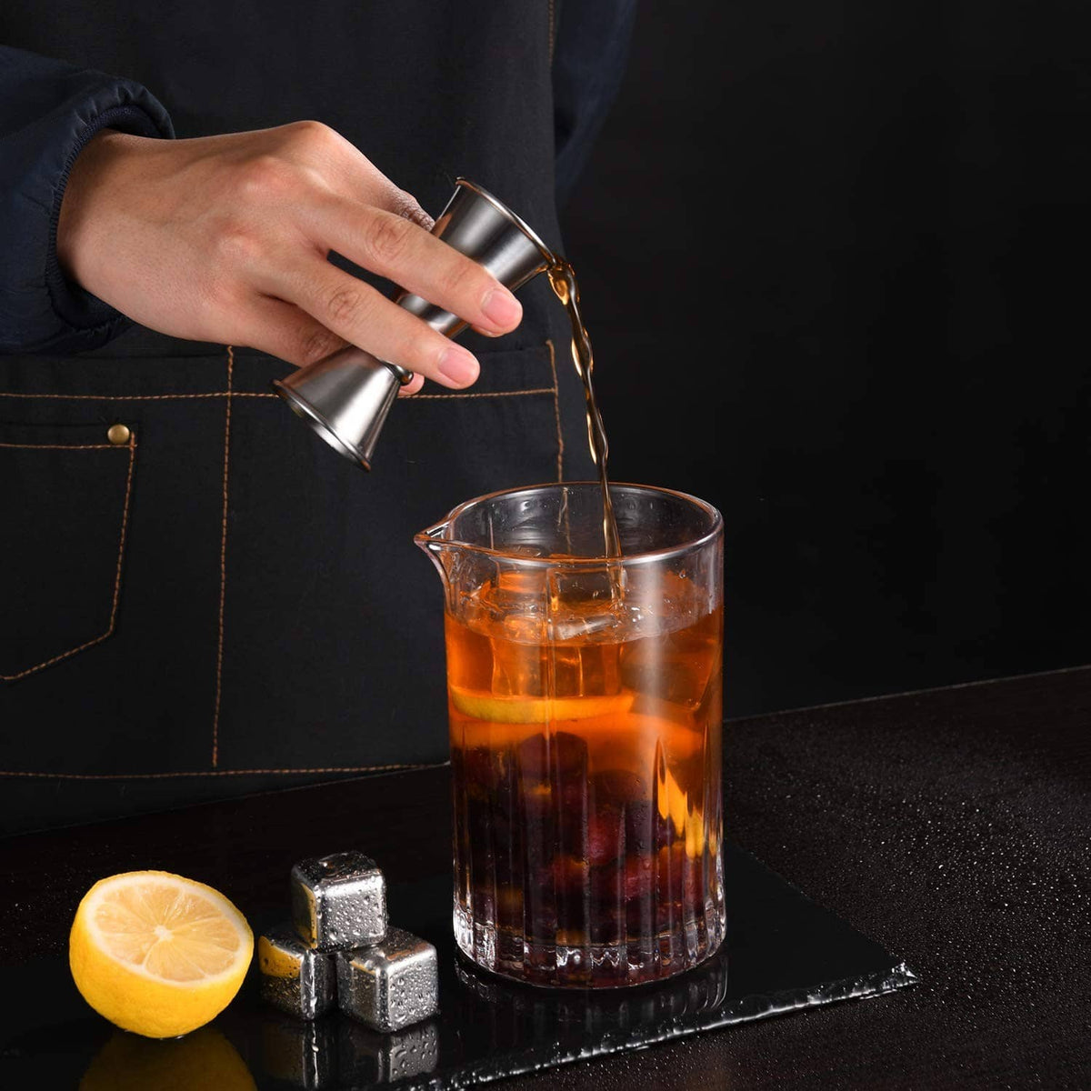 Stainless steel jigger pouring into a drink pitcher