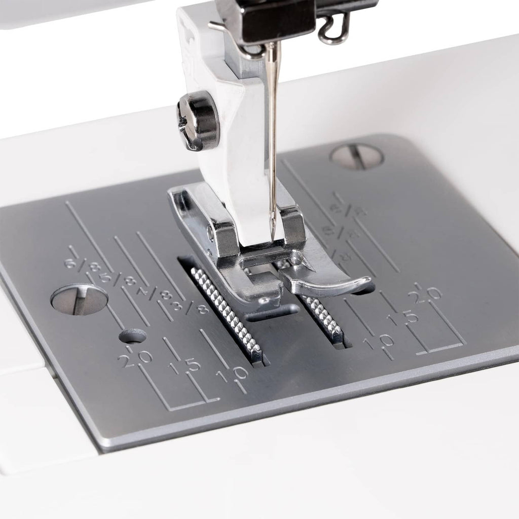 Sewing machine presser foot over gray fabric, close-up of needle and feed area