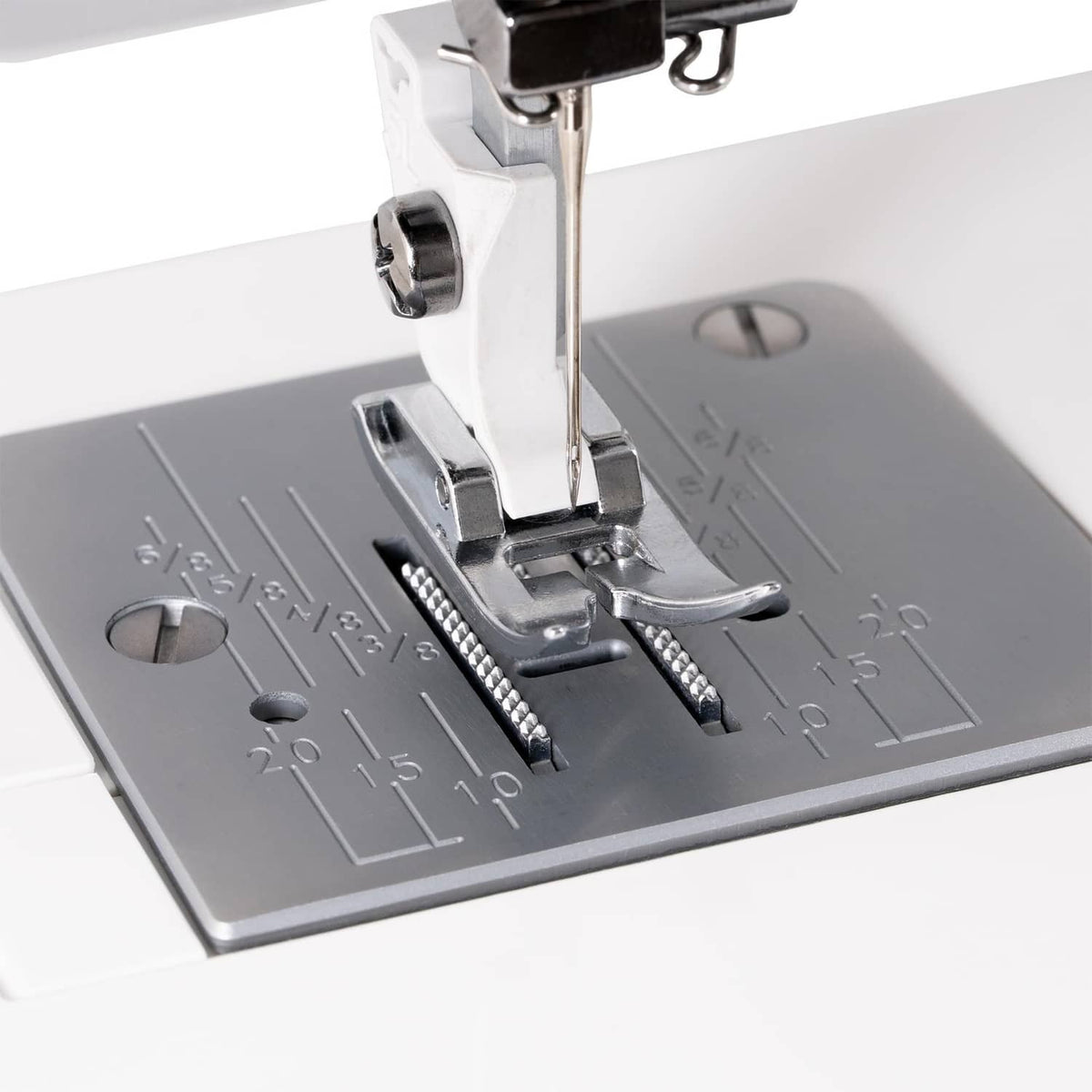 Sewing machine presser foot over gray fabric, close-up of needle and feed area