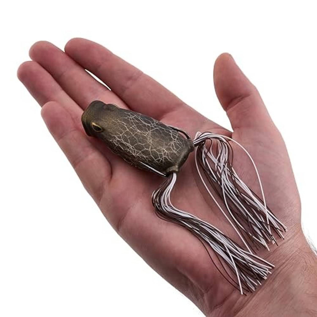 Frog popping fishing lure held in hand, dark mottled body and trailing skirt