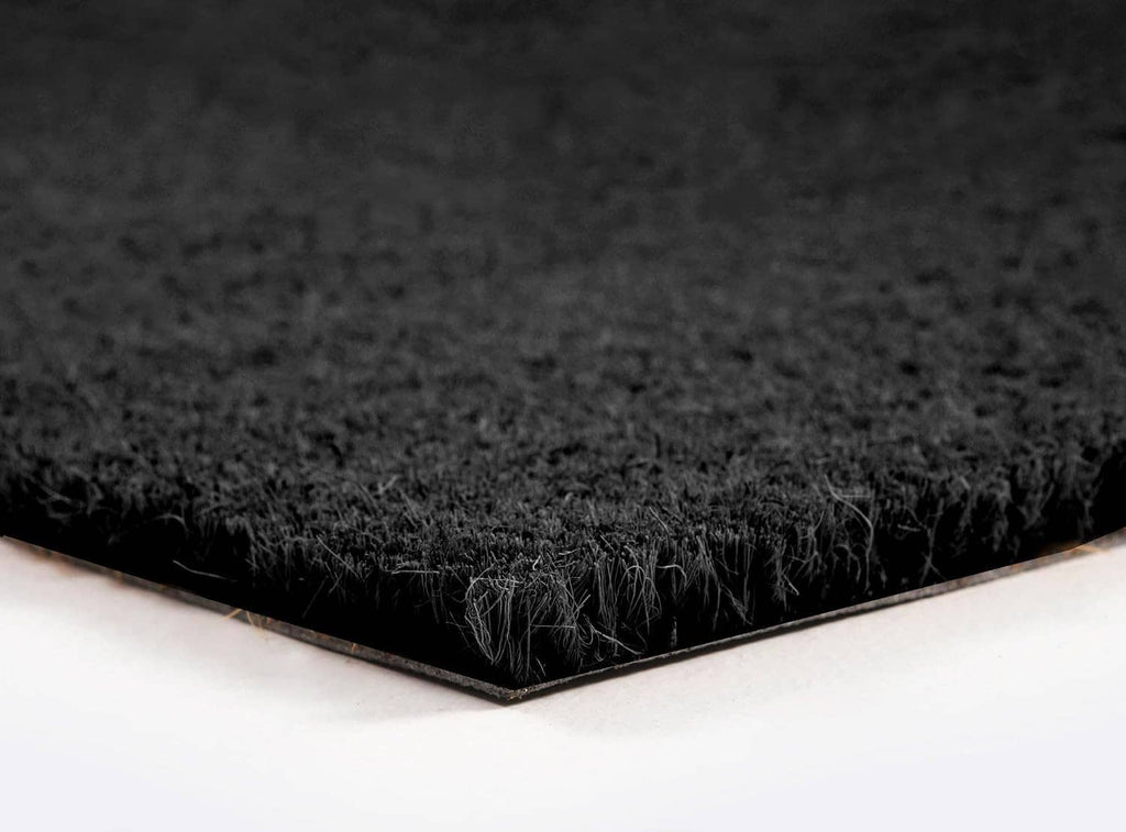 Close-up of black coir door mat corner with thin rubber backing