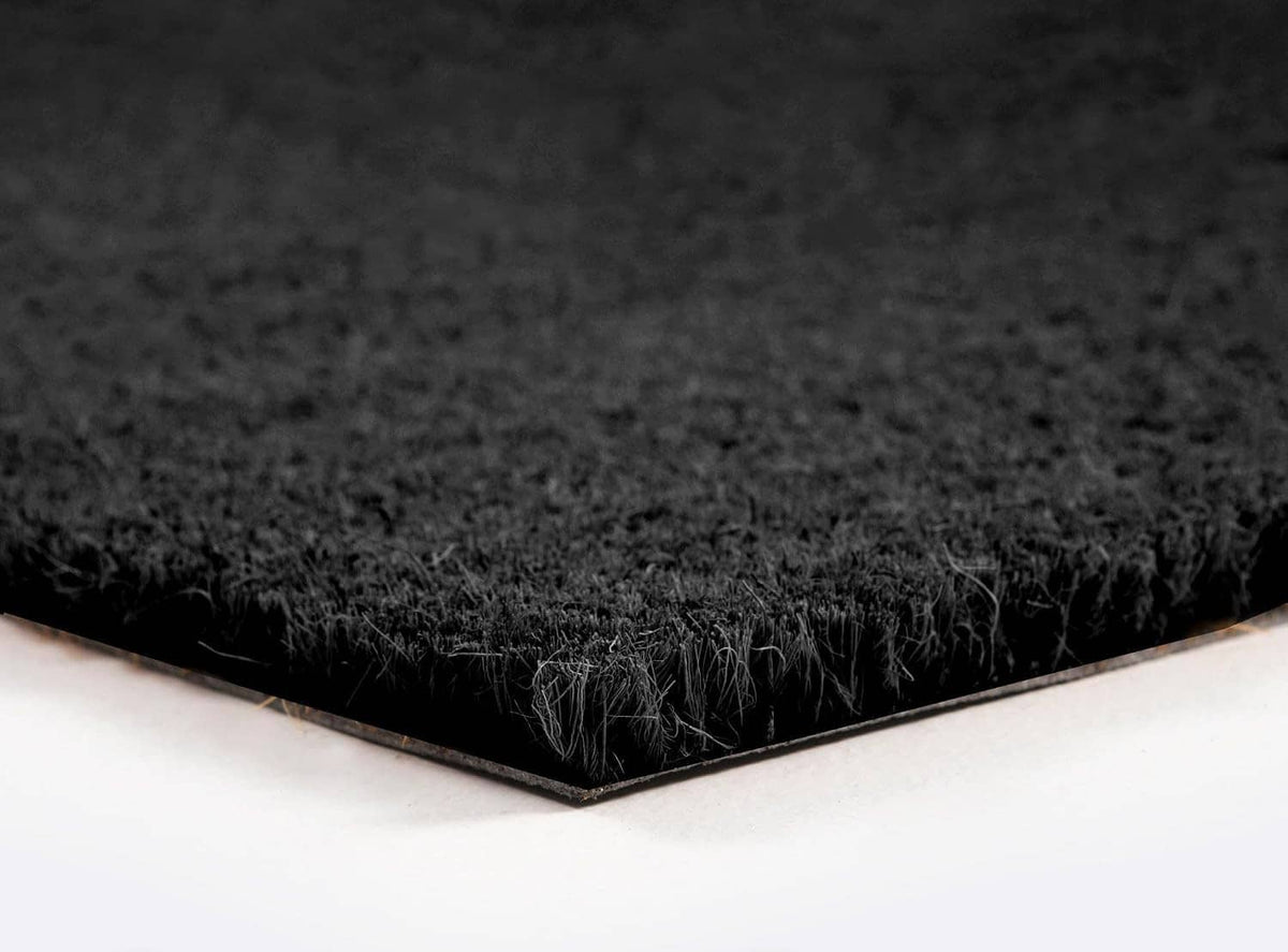 Close-up of black coir door mat corner with thin rubber backing