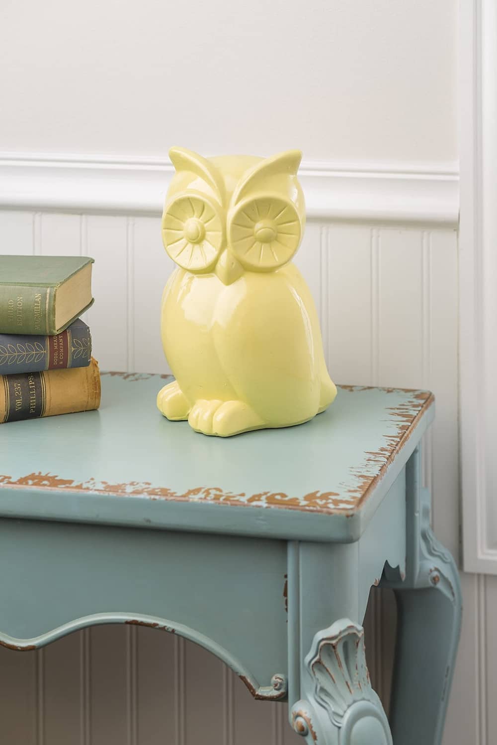 Yellow owl decorative figurine on a painted blue cabinet shelf