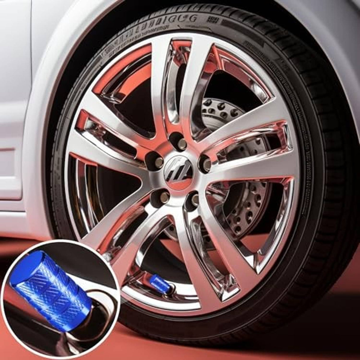 Blue tire valve stem cap shown beside a car wheel; anodized aluminum knurled texture