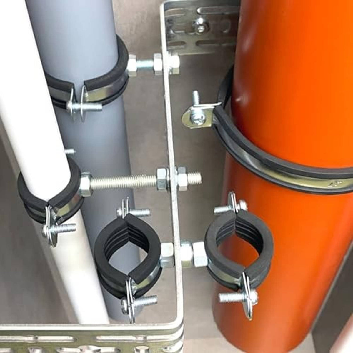 Pipe clamps securing gray and orange tubing with black rubber split rings and bolts