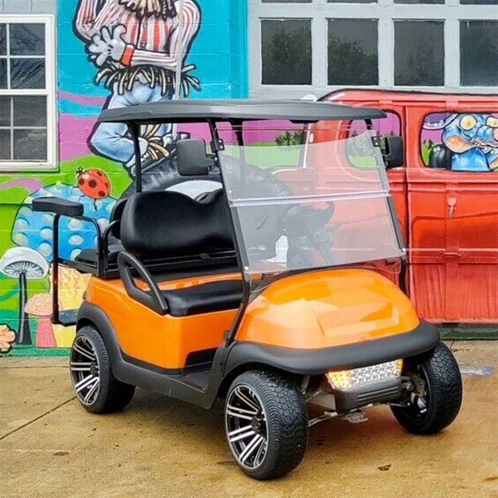 Clear folding golf cart windshield with black hinges installed on orange cart.