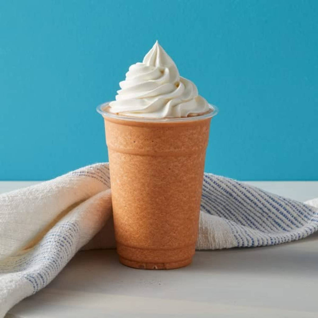Thai tea blended creme drink topped with whipped cream in a clear cup