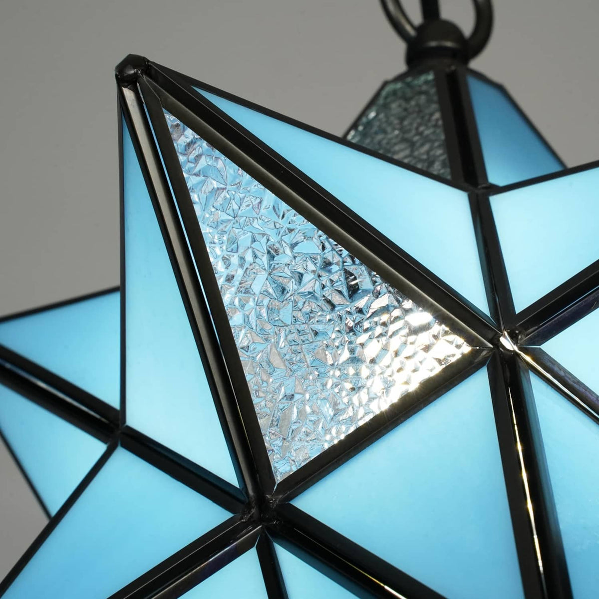 Close-up of blue stained glass star pendant light panel with black metal crossbars
