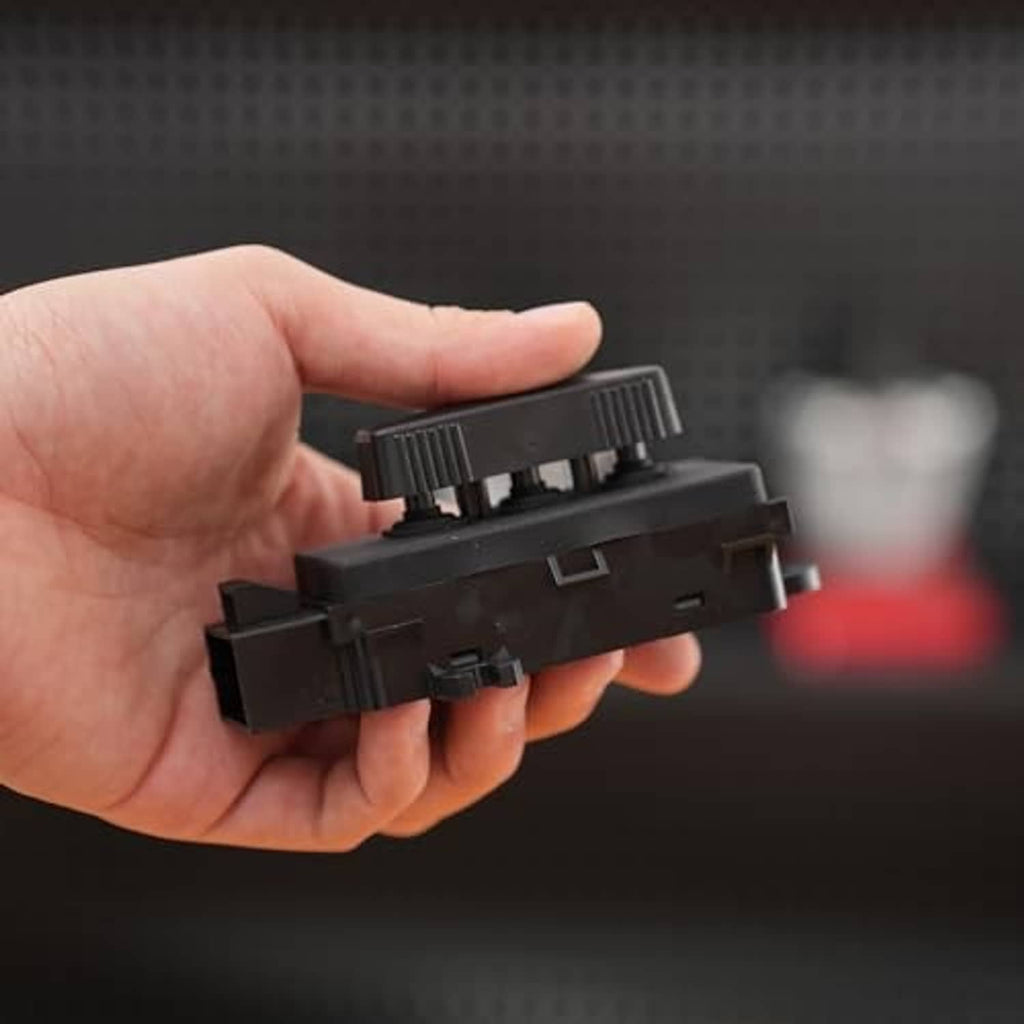 Black power seat switch held in hand, top knob and side tabs visible