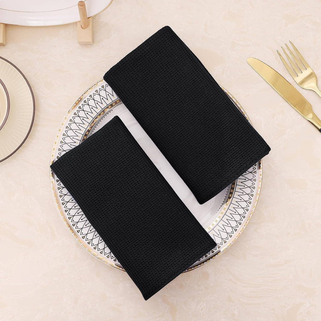 Black waffle weave cotton towels folded on a plate, set of multiple towels
