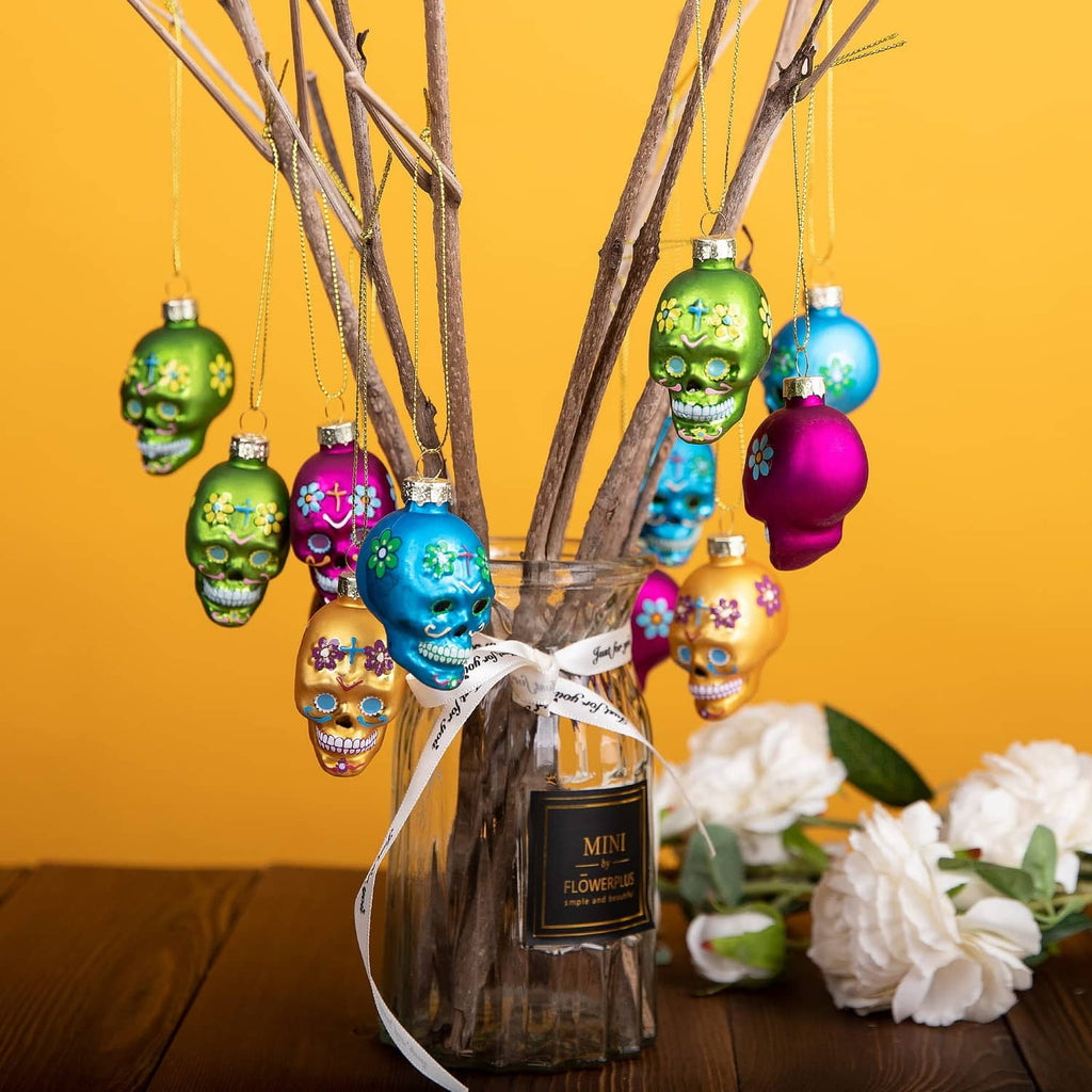 Assorted Day of the Dead glass skull ornaments hanging from bare branches