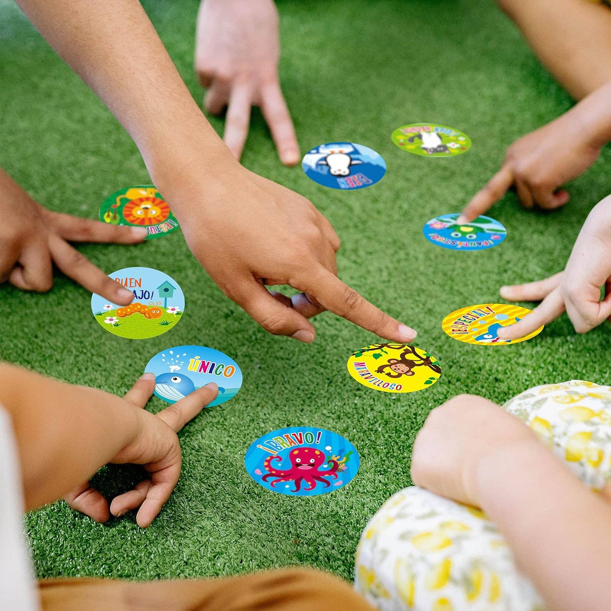Children placing round Spanish teacher reward stickers on green grass for a game