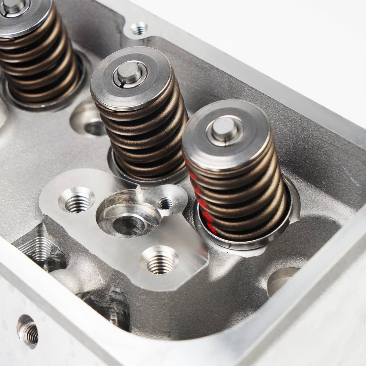 Close-up of aluminum cylinder head with valve springs, rocker studs, and fasteners