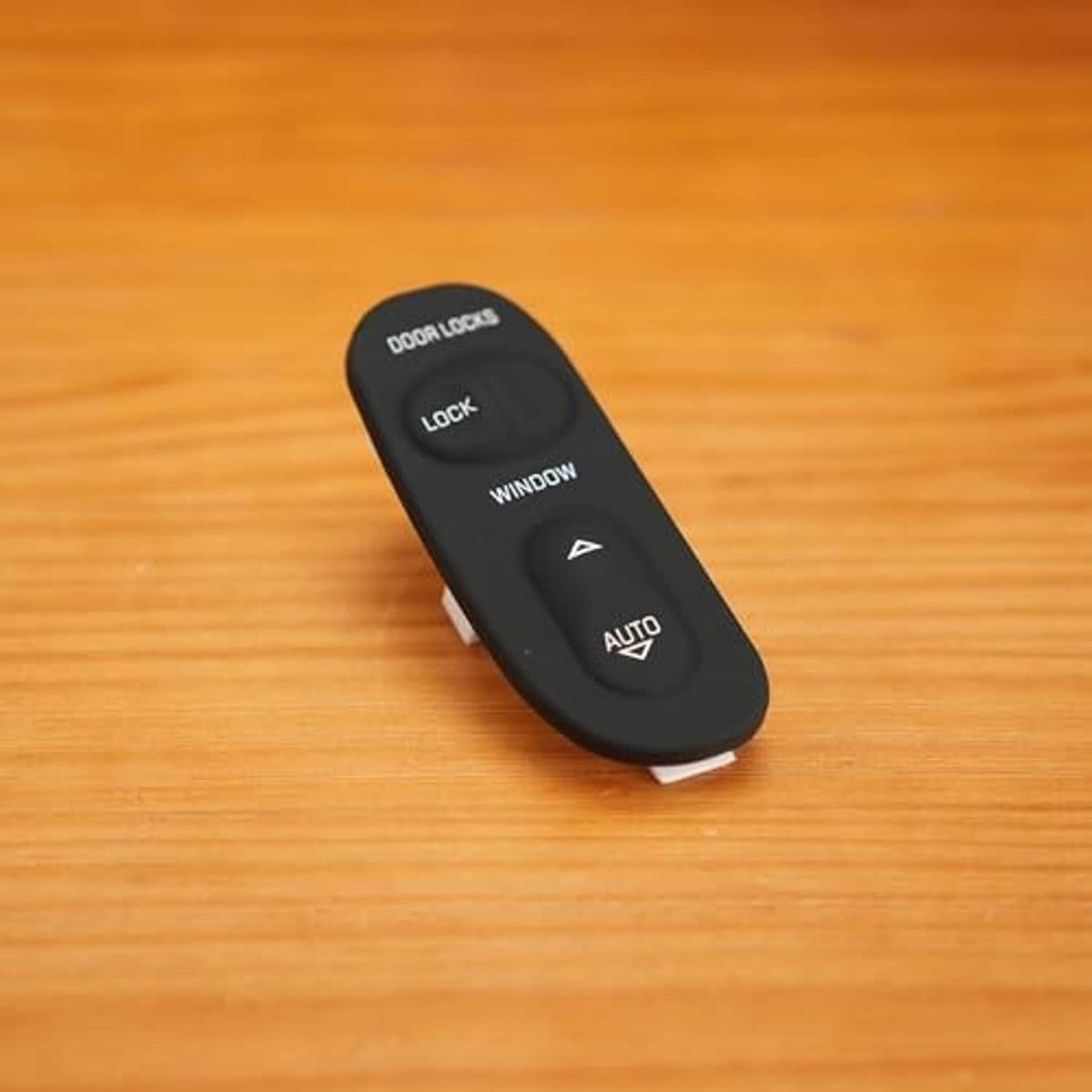 Black power window control switch on wood with door lock and AUTO window controls