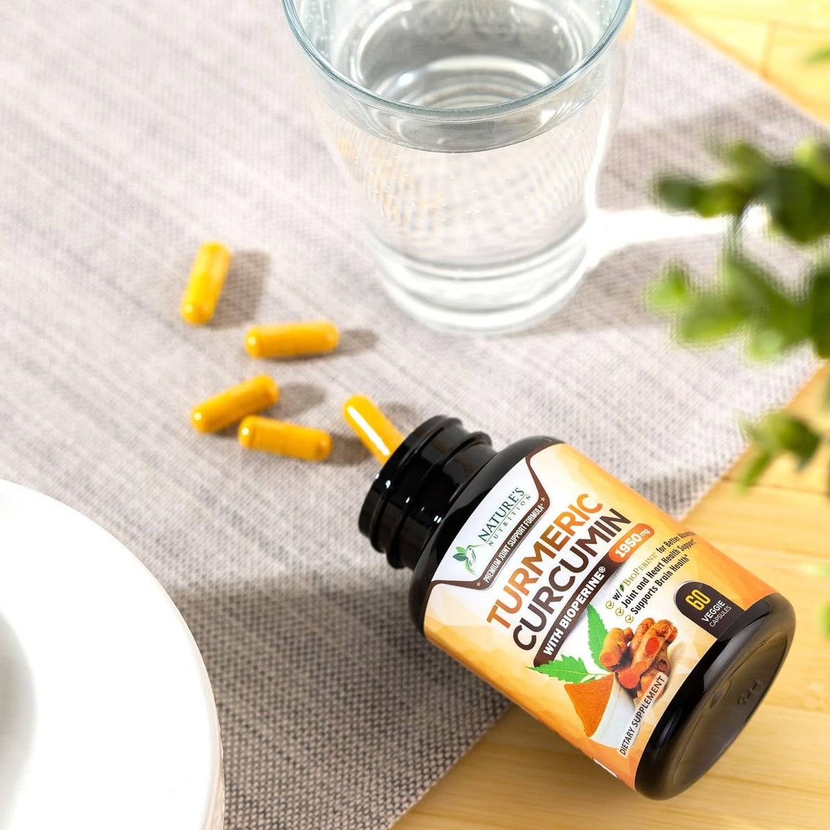 Turmeric curcumin supplement bottle with yellow capsules and glass of water