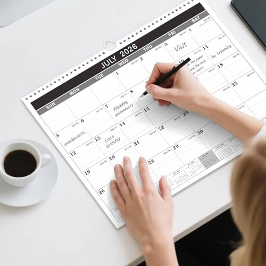 Wall calendar July 2026 with monthly grid, hands writing in a date